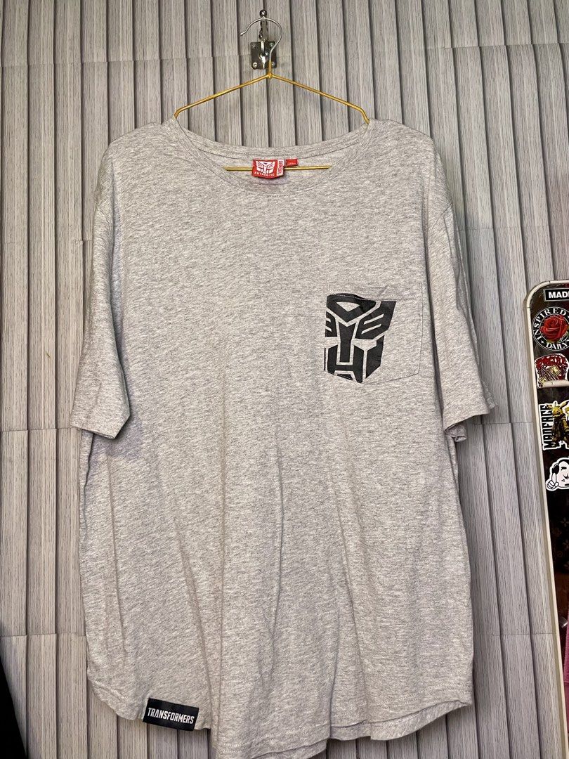 Transformers Authentic Grey T-Shirt XL (Category: Tshirts & Polo Shirts ) located in Manila. Submitted by fabufinds29 (Listing ID 1460561900, Image 1). Description: - Authentic Grey Transformers T-shirt - Size: XL - Features the iconic Autobot logo on the chest pocket - 'TRANSFORMERS' text printed on the back - Additional 'TRANSFORMERS' branding on a tag near the hem.