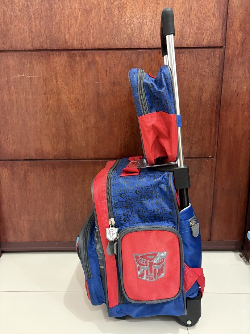 Transformers Rolling Backpack with Lunch Bag (Category: Backpacks) located in Manila. Submitted by kdp202 (Listing ID 1460639579, Image 2). Description: - Features cool Optimus Prime and Bumblebee graphics. - Includes a detachable lunch bag with the Autobot logo. - Stylish blue and red design with a Transformers pattern. - Ideal for school or travel. - Easy to pull with wheels and an extendable handle..