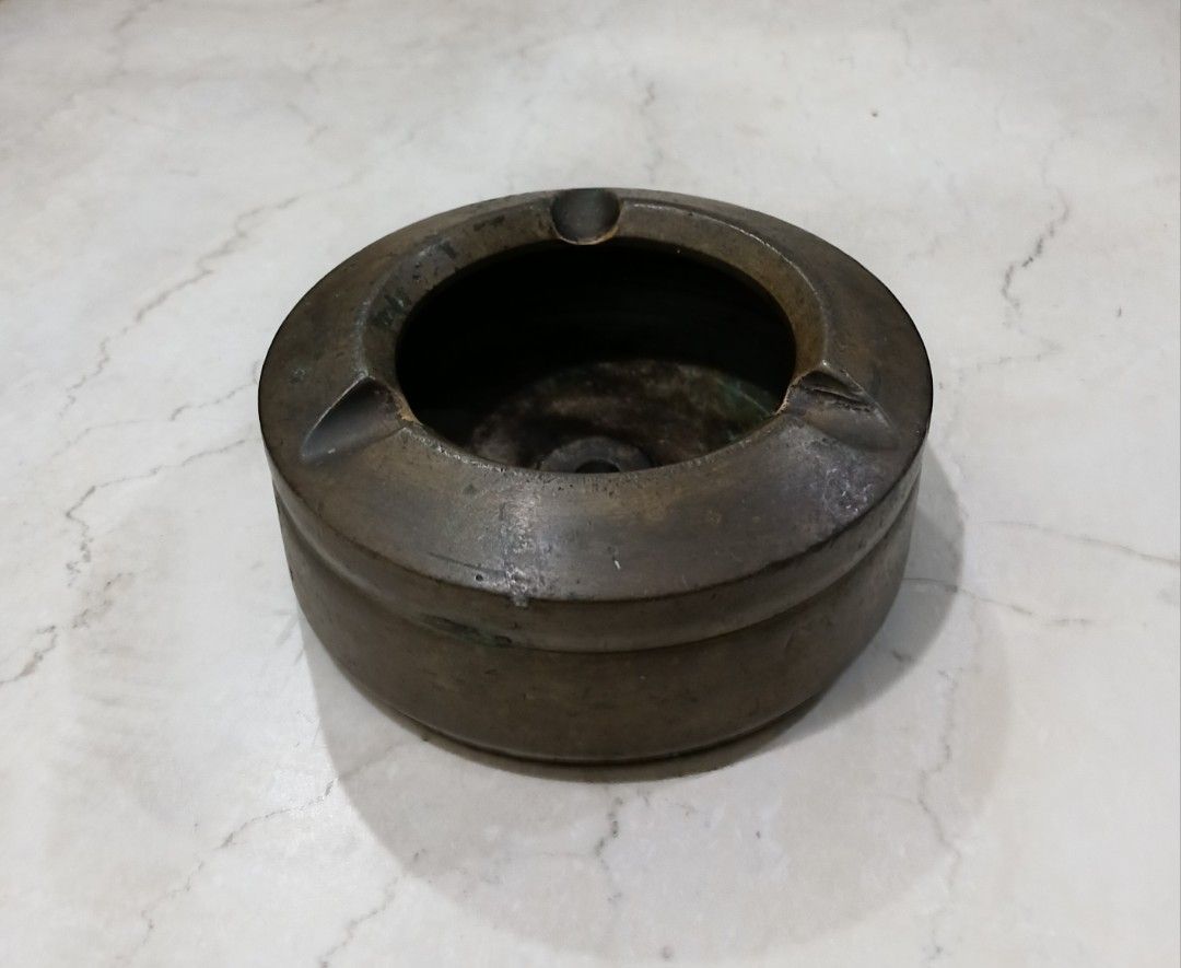 Vintage Heavy Solid Brass Tabletop Ashtray (1.3kg / 10.5cm) (Category: Vintage Collectibles) located in Bulacan. Submitted by honhonliz (Listing ID 1460613818, Image 1). Description: Material: Solid Brass / BronzeWeight: Heavyweight at 1.3 kg (1,300 grams) Dimensions: 10.5 cm diameter × 5 cm height Design: Round monolithic structure with a deep ash well and built-in cigarette/cigar rest slots. It features a raw, industrial aesthetic with clean gr