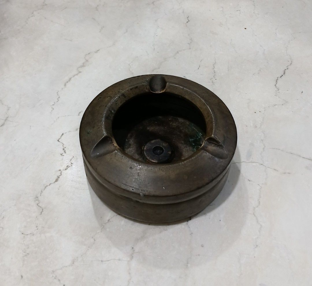 Vintage Heavy Solid Brass Tabletop Ashtray (1.3kg / 10.5cm) (Category: Vintage Collectibles) located in Bulacan. Submitted by honhonliz (Listing ID 1460613818, Image 2). Description: Material: Solid Brass / BronzeWeight: Heavyweight at 1.3 kg (1,300 grams) Dimensions: 10.5 cm diameter × 5 cm height Design: Round monolithic structure with a deep ash well and built-in cigarette/cigar rest slots. It features a raw, industrial aesthetic with clean gr