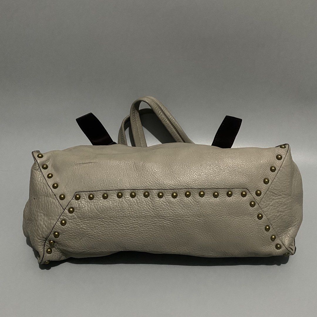Vtg PRADA Talco Nappa Aviator Bag (Category: Shoulder Bags) located in Mandaue City. Submitted by dfindss. (Listing ID 1460688016, Image 2). Description: Prada Talco Nappa Leather Aviator Studded Tote Bag (Model BR4147). It features an off-white/greyish talco nappa leather body accented with dark brown leather buckle straps, brass hardware, and edgy studded rows framing the sides ISSUE: Missing Emblem .