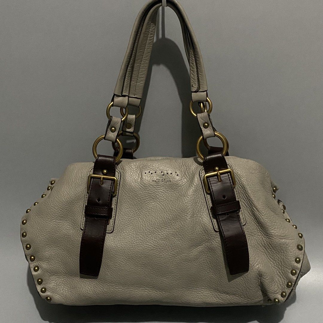 Vtg PRADA Talco Nappa Aviator Bag (Category: Shoulder Bags) located in Mandaue City. Submitted by dfindss. (Listing ID 1460688016, Image 1). Description: Prada Talco Nappa Leather Aviator Studded Tote Bag (Model BR4147). It features an off-white/greyish talco nappa leather body accented with dark brown leather buckle straps, brass hardware, and edgy studded rows framing the sides ISSUE: Missing Emblem .
