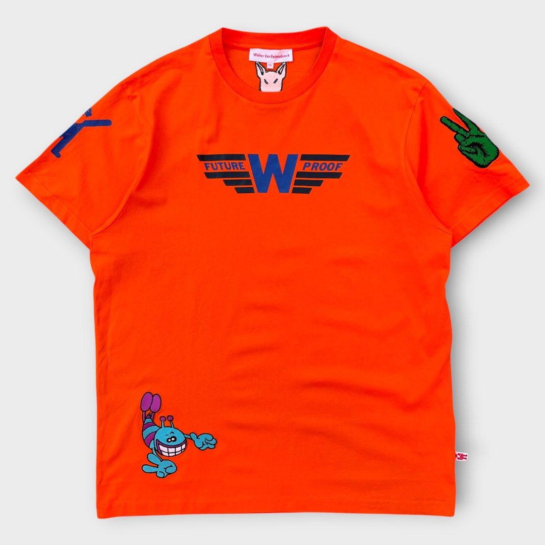 Walter Van Beirendonck - Past Present Future Shirt (Category: Tshirts & Polo Shirts ) located in Los Banos. Submitted by declutterking (Listing ID 1460703743, Image 2). Description: Size XXL on tag Walter's classic characters printed and embroidered on an orange cotton t-shirt. Walterman logo tag on the side left seam. Dimensions: 18.75" shoulders 23.25" chest 30" length 8.75" sleeves Good as new condition Authentic.