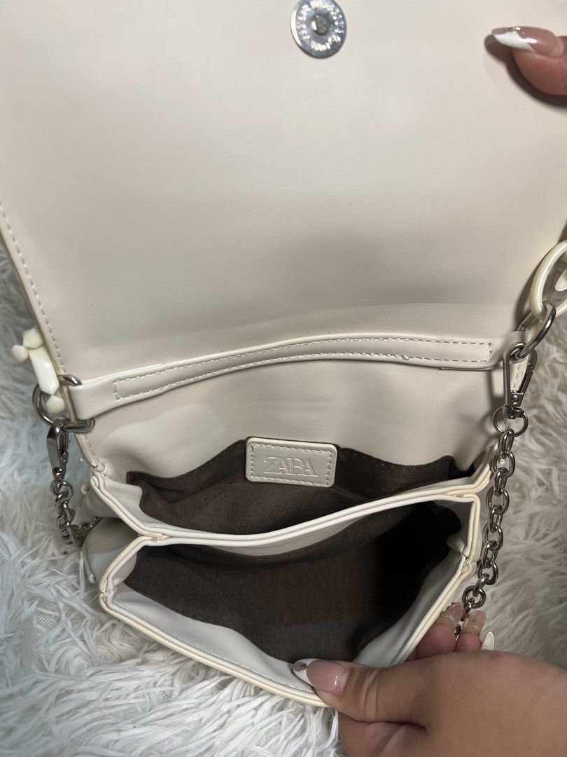 Zara White Ruched Chain Shoulder Bag (Category: Shoulder Bags) located in Manila. Submitted by yanya97 (Listing ID 1460536556, Image 2). Description: - Chic white ruched shoulder bag from Zara. - Features a trendy chunky white chain on the front. - Includes a detachable thin silver chain strap for versatility. - Secure magnetic snap closure. - Multiple compartments inside for organization. - Ideal accessory for your next night out..